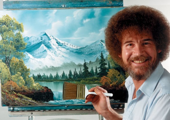 Photograph of Bob Ross in front of one of his beautiful signature mountain paintings