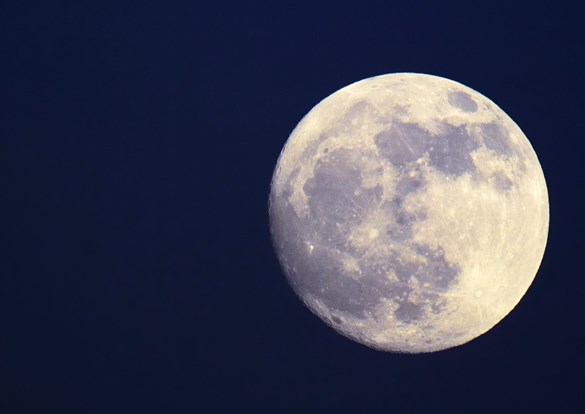 Closeup photograph of a full moon against a dark blue sky