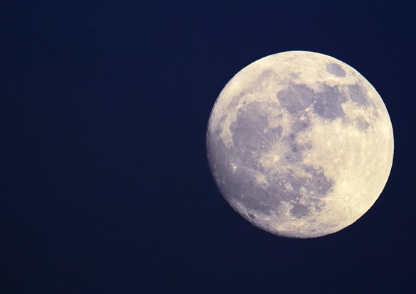 Closeup photograph of a full moon against a dark blue sky