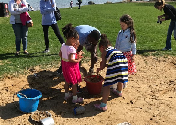 Small children filling buckets and playing in the sand