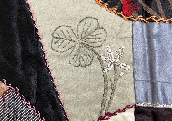 Patchwork quilt with hand-sewn panels and embroidered flower designs.