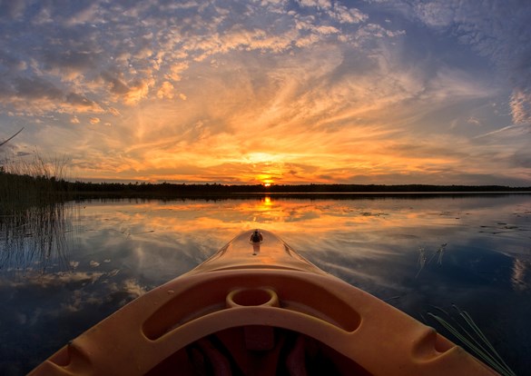 View of a beautiful sunset over the bow of a kayak on the lake