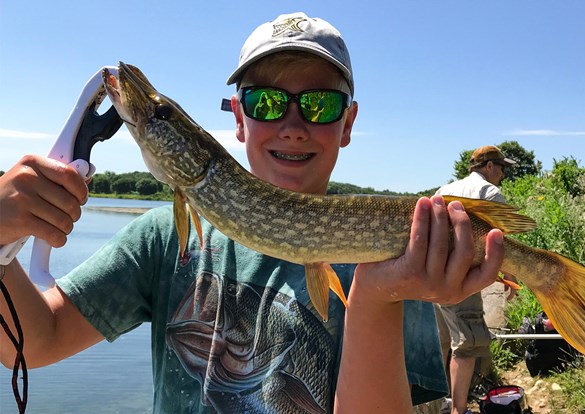 Young boy with a big smile, holding a large fish he just caought.