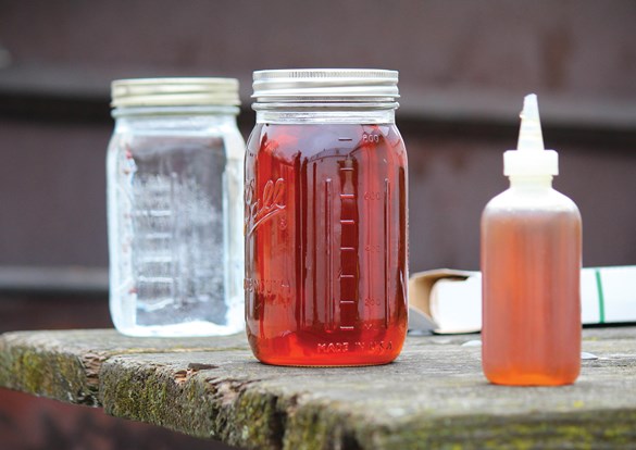 Bottles filled with freshly tapped maple syrup setting on a picnic table.