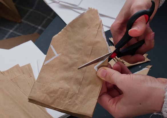 Person cutting apart brown paper bag for decoupage