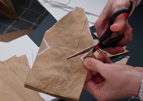 Person cutting apart brown paper bag for decoupage