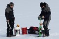 Two men drilling a hole in the ice