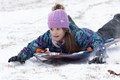 Young girl in a purple hat sledding down the hill