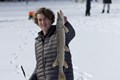 Young man holding up a northern pike caught while ice fishing