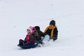 Three people on a large sledding going down the hill