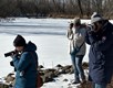 Volunteer photographers taking photos along the frozen banks of a river..