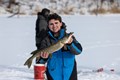 Yound man holding up a northern pike caught while ice fishing