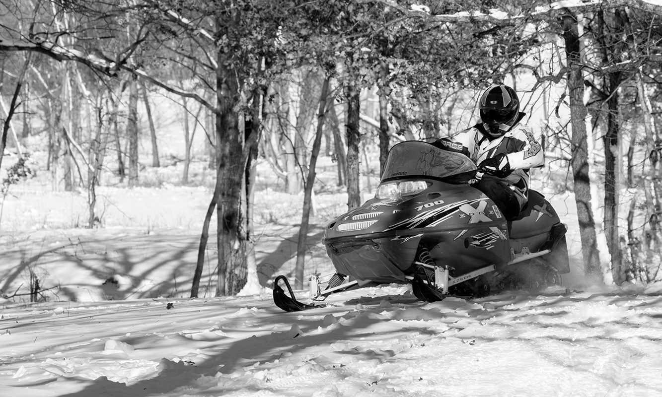 Bright red snowmobile racing through the woods