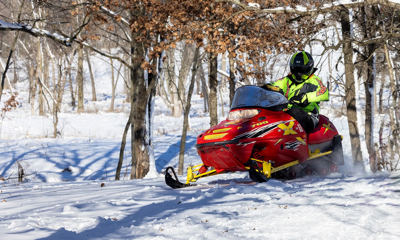 Bright red snowmobile racing through the woods