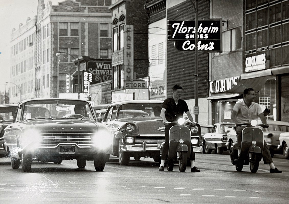 Vintage photo of cars and scooters driving through the city